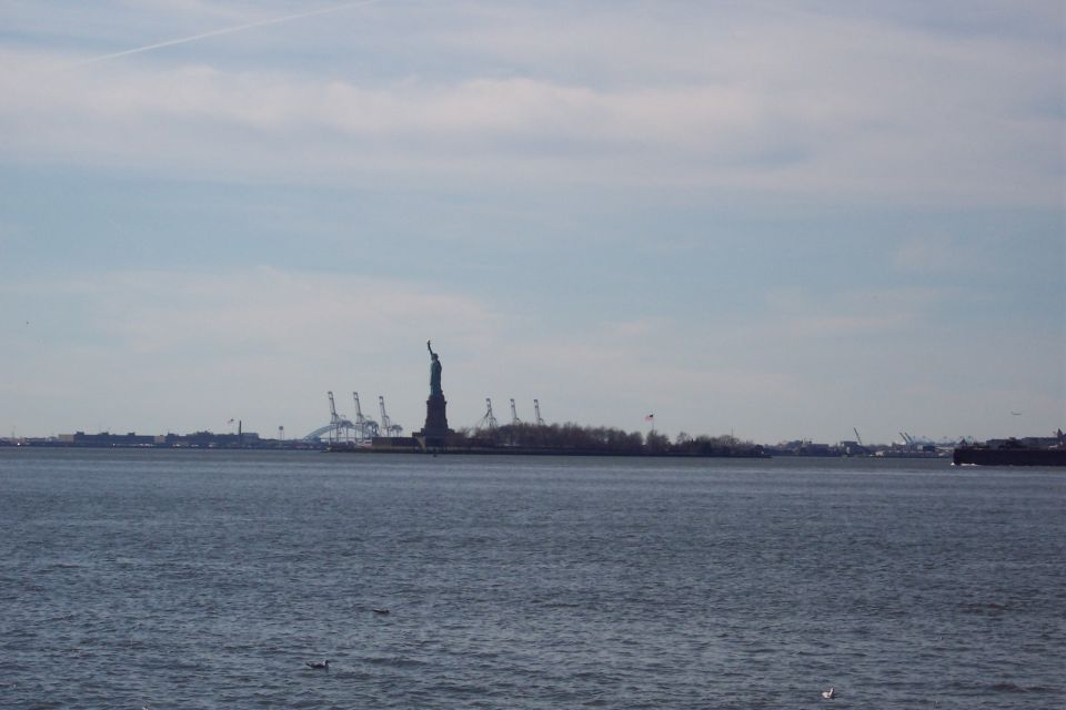 Statue of Liberty in New York Harbor with industrial cranes in the background