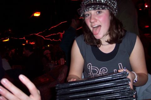 2001 Ford Crown Victoria - A woman playfully sticks her tongue out while holding a stack of menus in a dimly lit establishment.