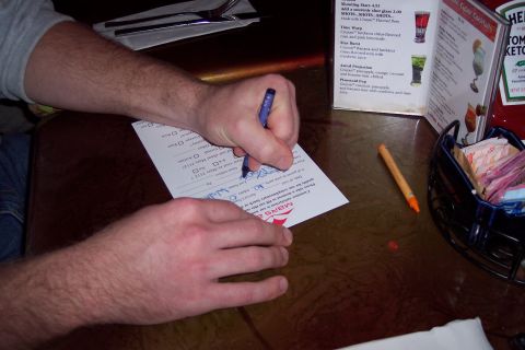 2001 Ford Crown Victoria - A person fills out a form on a table, with a menu and ketchup bottle visible.