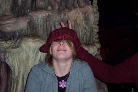 2001 Ford Crown Victoria - A person playfully poses with a hat covering their eyes and a bunny ear gesture made by someone behind them.