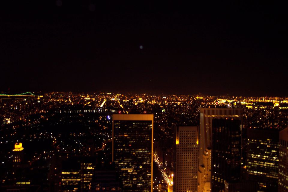 New York City skyline at night with illuminated buildings and a distant bridge