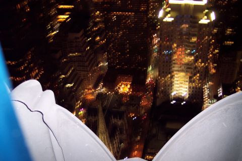 2001 Ford Crown Victoria - A blurry nighttime cityscape with illuminated buildings and streets, seen from a high vantage point.