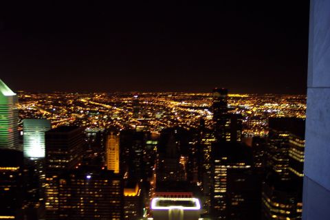 2001 Ford Crown Victoria - Nighttime skyline view from a high observation deck, looking out over a dense grid of lit skyscrapers and city streets stretching to the ho…