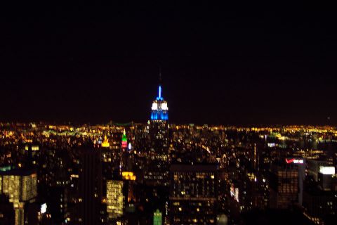 2001 Ford Crown Victoria - The Empire State Building is illuminated against the dark night sky, overlooking a cityscape.