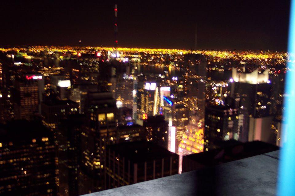 Blurry view of New York City skyline at night with illuminated buildings and distant lights
