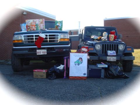 1996 Ford Bronco - Two vehicles are parked outside a building, decorated with toys and a Christmas stocking for a toy drive.