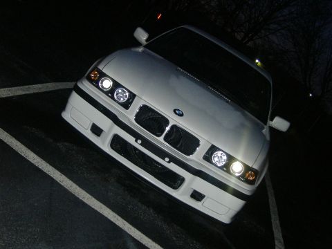 2001 BMW 3 Series - The front of a white BMW E36 coupe is shown at night, parked in a lot.