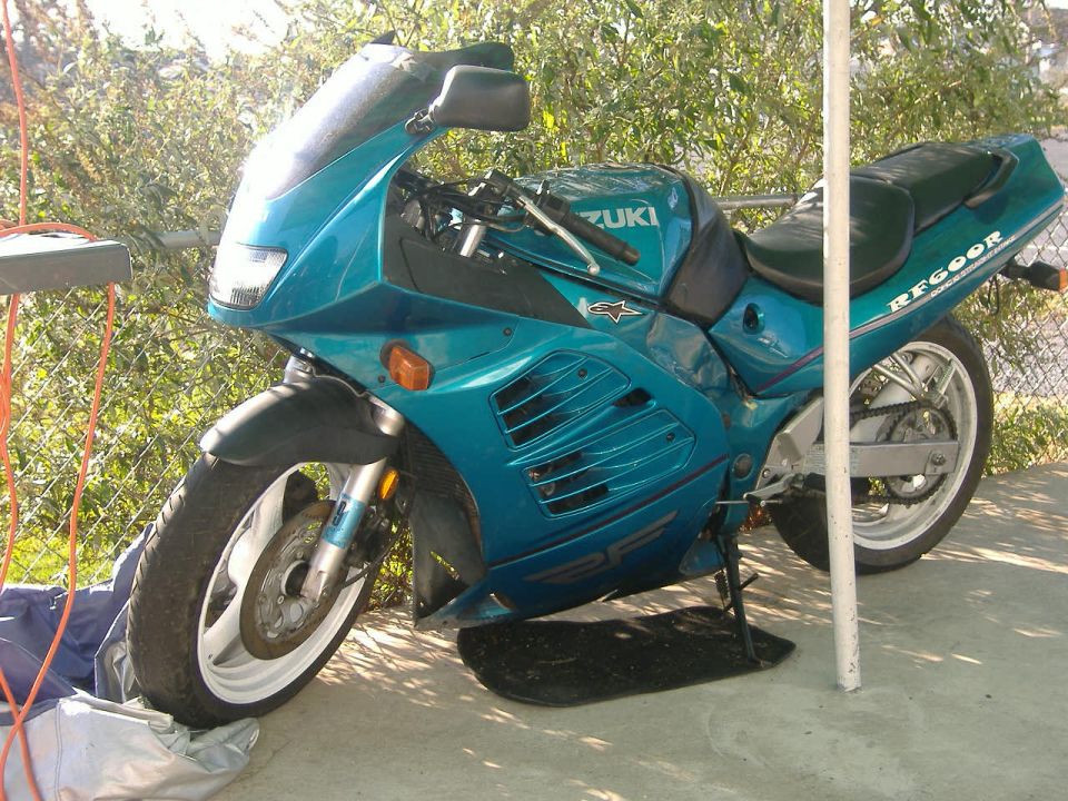 Teal Suzuki motorcycle with black seat and "RF600R" text on the tail, parked outdoors