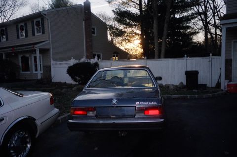 1983 BMW 5 Series - The rear of a dark blue 1983 BMW 633CSi is visible, parked next to a white car in a residential driveway.