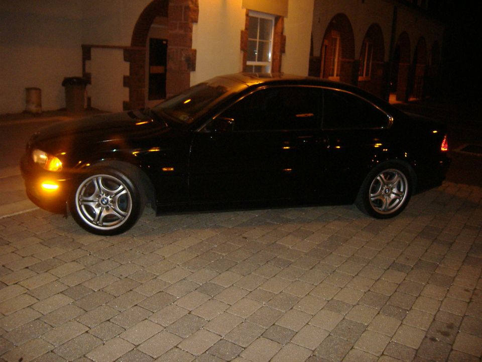 Black 2001 BMW 3 Series coupe parked on brick pavers at night