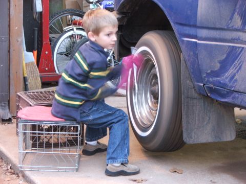 1990 Dodge Shadow - A young boy cleans the wheel of a blue car while it is in motion.