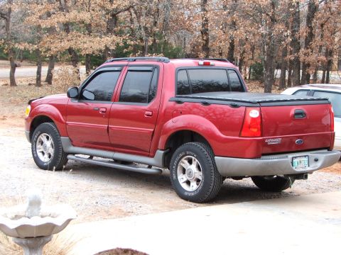 2003 Ford Sport Trac - This red 2003 Ford Sport Trac is parked outdoors with trees in the background.