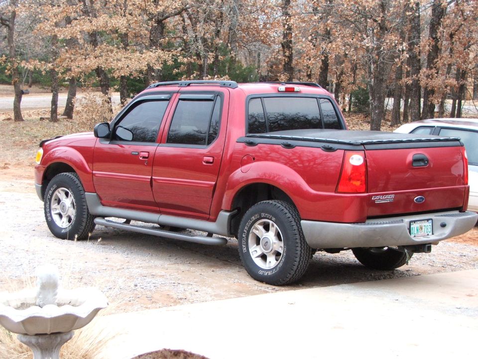 Red 2003 Ford Sport Trac pickup truck, rear 3/4 view, with a soft tonneau cover