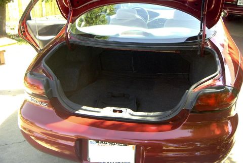 1999 Ford Taurus - The trunk of a red sedan is open, revealing the cargo area and the rear of the vehicle.