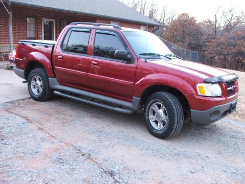 2003 Ford Sport Trac - This red 2003 Ford Sport Trac pickup truck is viewed from the front three-quarter angle on a gravel surface.