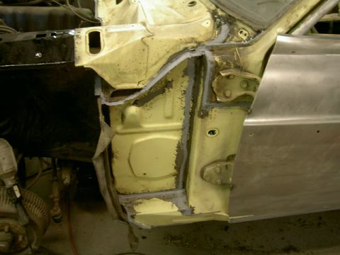 1967 Ford Ranchero - Close-up view of a car's door frame undergoing repair, showing welding and new metal panel installation.