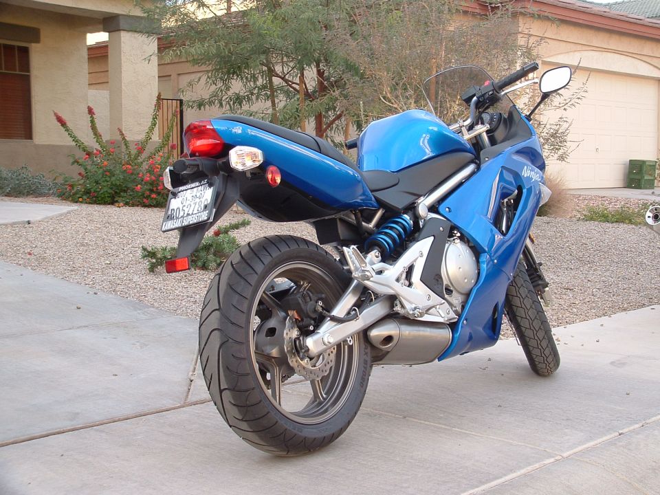 Blue Kawasaki Ninja motorcycle parked on a driveway, rear 3/4 view. License plate reads R05278