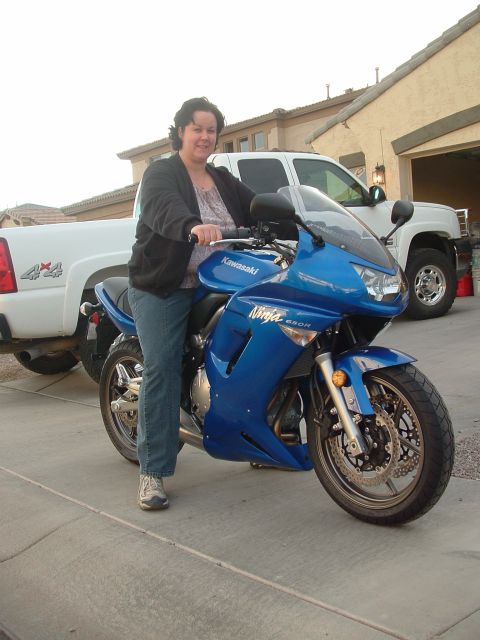 2007 Kawasaki Ninja - Woman sits on a blue 2007 Kawasaki Ninja 650R motorcycle in front of a house and a white pickup truck.