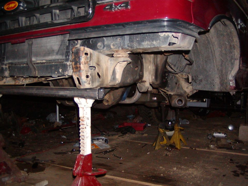 Red 1991 Ford Bronco front end on jack stands, showing suspension and frame