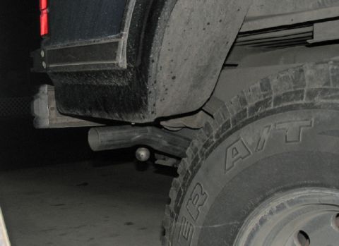 1984 Ford Bronco - Close-up view of the rear bumper and exhaust pipe on a dark-colored SUV.