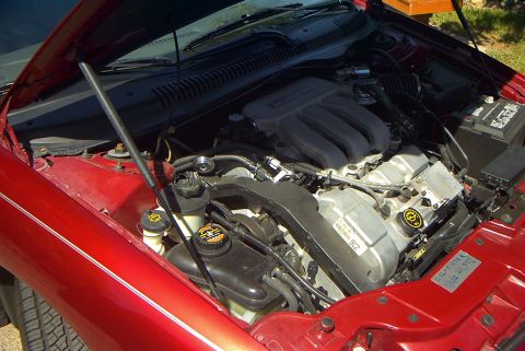 1999 Ford Taurus - The engine compartment of a red car, showing the V-shaped engine and associated components.