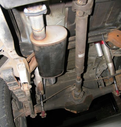 1984 Ford Bronco - Close-up view of the undercarriage, focusing on the exhaust system and drivetrain components.