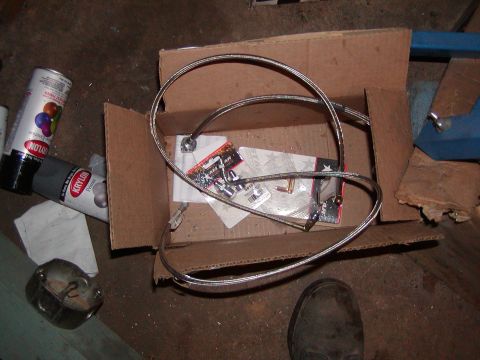 1991 Ford Bronco - A box contains new brake lines and other parts, next to spray paint cans on a workshop floor.