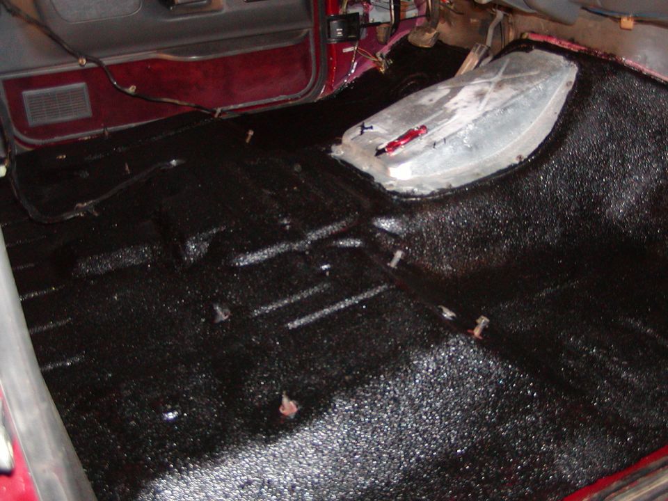 Vehicle interior floor with black spray-on bedliner and exposed metal tunnel cover