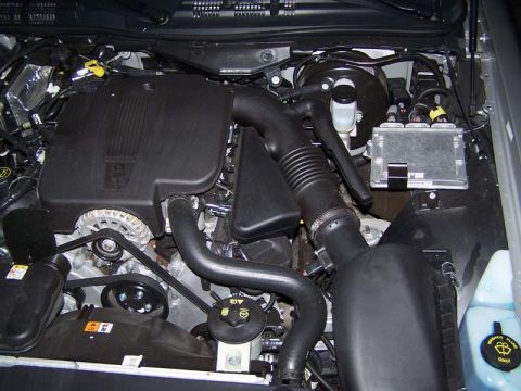 1998 Ford Crown Victoria - Engine bay of a vehicle showing a V8 with black plastic intake covers, air intake tube and accessory components.