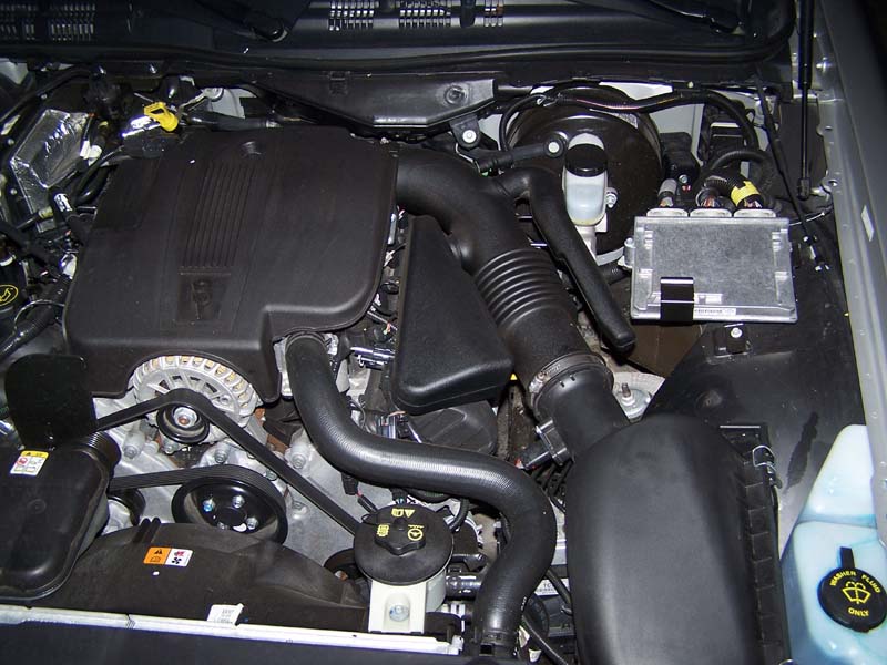 V8 engine bay with black plastic intake covers and air intake tube