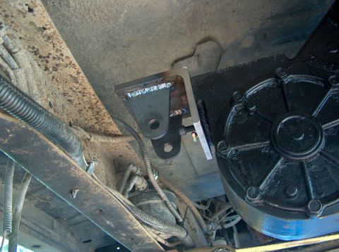 1991 Ford Bronco - Close-up view of a custom bracket welded to the underbody of a vehicle, near a black mechanical component.