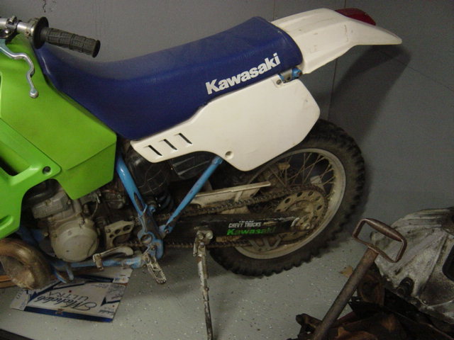 Side view of green and white Kawasaki dirt bike with blue seat