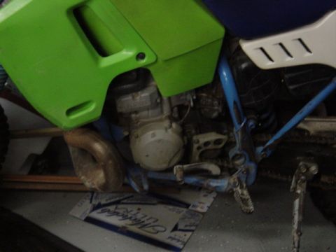 1987 Suzuki Samurai - Close-up view of a dirt bike's engine and frame components, with green body panels and blue frame tubes.