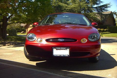 1999 Ford Taurus - Front view of a red 1999 Ford Taurus parked outdoors.