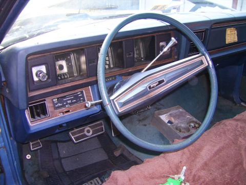 1971 Mercury Marquis - The interior of a car features a blue dashboard with wood grain accents and a prominent steering wheel.