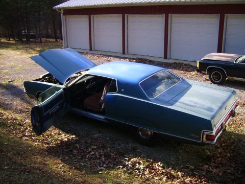 1971 Mercury Marquis - A blue 1971 Mercury Marquis coupe sits with its hood and driver door ajar, parked in front of a red-sided garage.