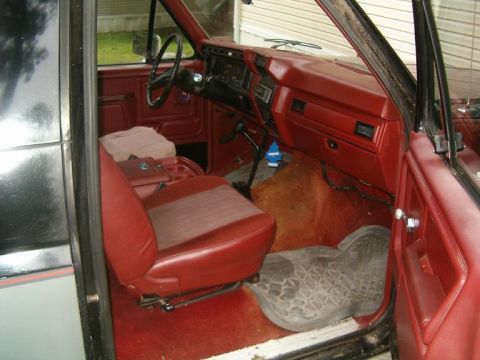 1986 Ford Bronco - Interior view of a 1986 Ford Bronco, showing the red seats, dashboard, and floor mats.
