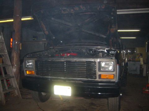 1986 Ford Bronco - Front view of a black SUV with its hood open, revealing the engine compartment. The vehicle appears to be in a workshop or garage setting.