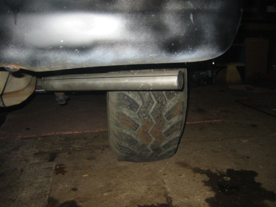 Close-up of a large tire and exhaust pipe under a vehicle
