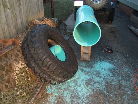1980 Jeep CJ5 - The rear of a 1980 Jeep CJ5 is visible behind a large tire and a section of pipe.