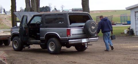 1978 Ford Bronco - A person walks away from a Ford Bronco with its hood and driver's door open, carrying a toolbox.