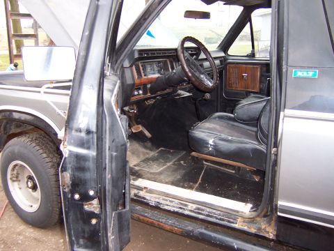 1978 Ford Bronco - The interior of a 1978 Ford Bronco shows worn black seats and wood-grain accents on the dashboard and door panels.