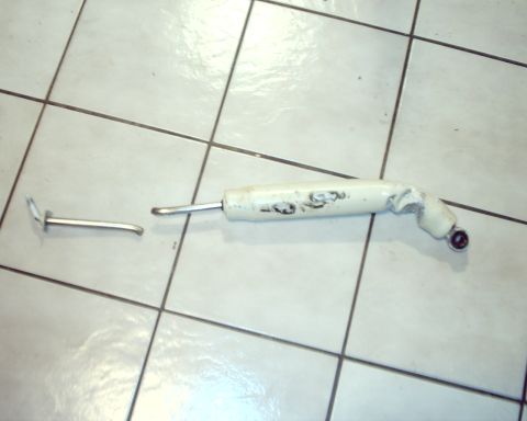 1979 Ford Bronco - A white shock absorber and a separate metal linkage piece are shown on a tiled surface.