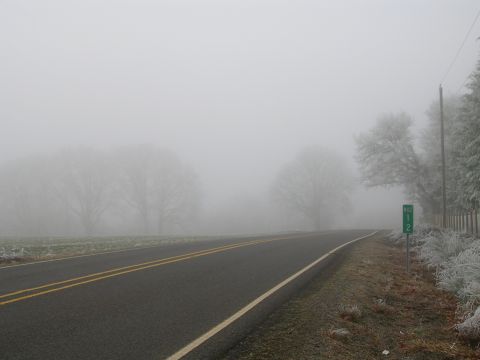 1996 Ford Probe - A desolate road disappears into thick fog, with a mile marker indicating "MILE 1 2" on the right side.