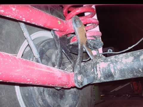 1984 Ford Bronco - Close-up view of the red painted rear suspension components and tire of a vehicle.