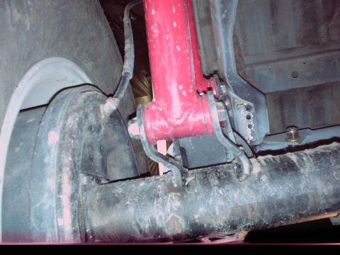 1984 Ford Bronco - Close-up view of a vehicle's rear axle, brake drum, and red shock absorber.