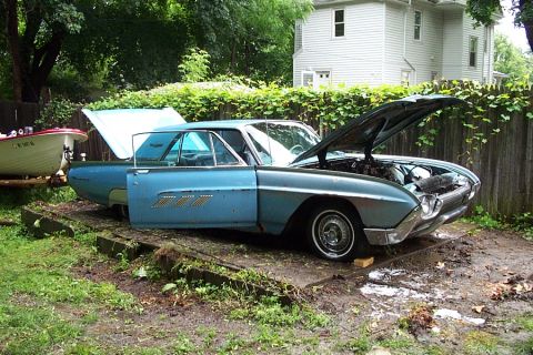 1978 Ford Bronco - A vintage blue Ford Thunderbird sits in a yard with its hood and door open, appearing to be undergoing maintenance.