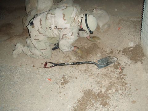 1996 Ford Probe - A soldier is digging in the dirt with a shovel, with sandbags piled up behind him.