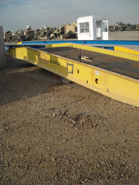 1996 Ford Probe - A yellow trailer sits on a gravel lot, with a collection of military vehicles visible in the distance.