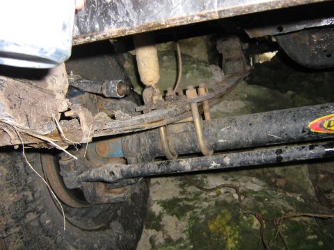 1986 Ford Bronco - Undercarriage view of a vehicle's suspension system, showing leaf springs and shock absorber.